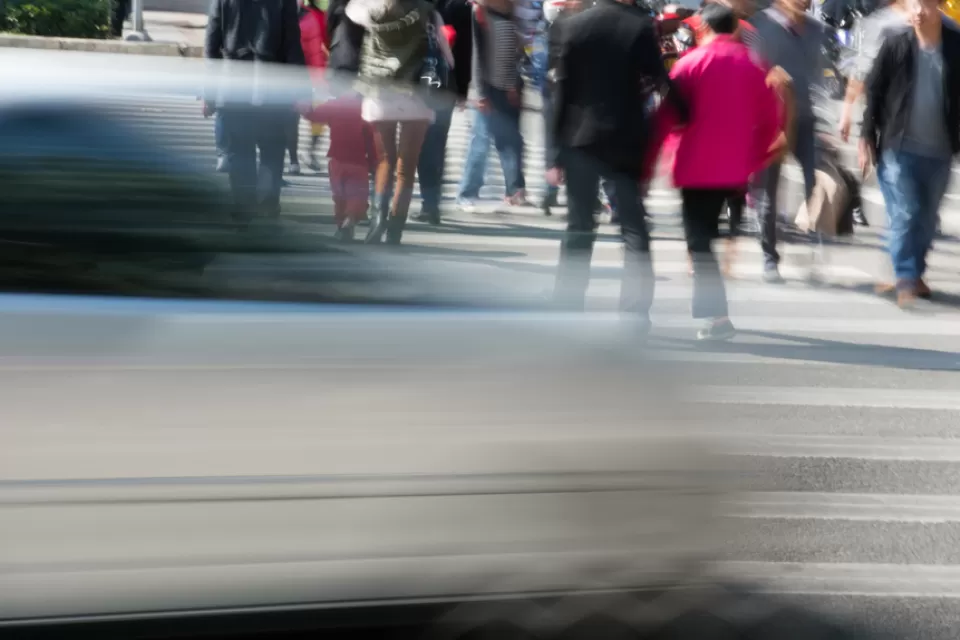 People in crosswalk with blurred fast car passing in foreground